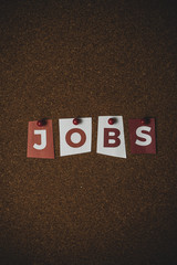 The word Jobs written on colorful note papers on board background. Employment concept. Job search. 