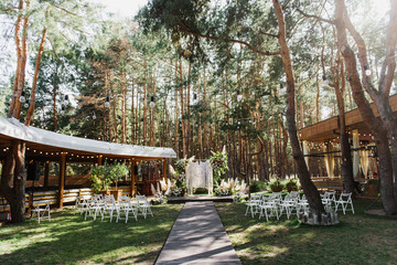 Beautiful wedding ceremony with an arch in boho style in the forest.