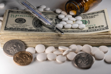 Stack of American money with medicine, pills and clinical thermometer on stack of Dollar cash