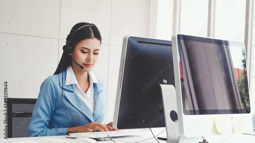 Poster customer support agent or call center with headset works on desktop computer while supporting the cu