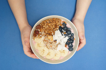 Child holds in hand Handmade Bowl with healthy tasty breakfast