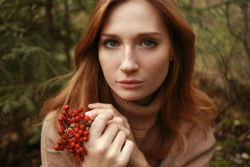 Beautiful red head girl in sweater in forest
