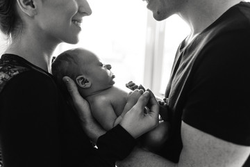 Black and white photo of young parents with a newborn.