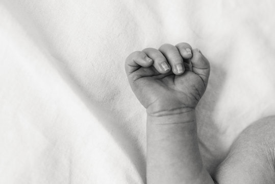 Black-white photograph of a newborn's hand closeup.