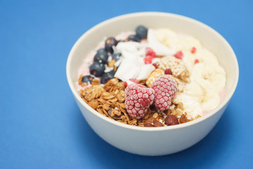 Handmade Bowl healthy tasty breakfast of yogurt, smoothie with granola, nuts, bananas and berries