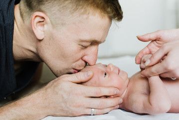 Young dad kisses a newborn.