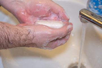 Fototapeta premium Personal hygiene and prevention of the coronavirus pandemic wash men's hands with soap and water.