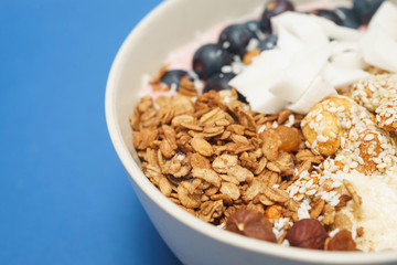 Handmade Bowl healthy tasty breakfast of yogurt, smoothie with granola, nuts, bananas and berries