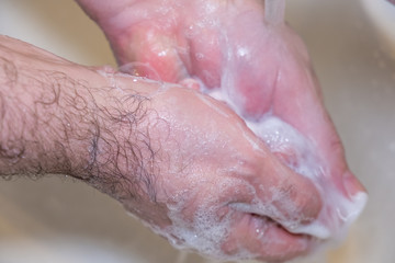 Fototapeta premium Personal hygiene and prevention of the coronavirus pandemic wash men's hands with soap and water.