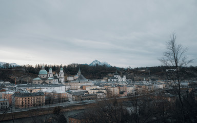 Panoramic view of Salzburg against snowcapped mountains and overcast sky