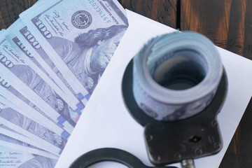 twisted wad of dollars buttoned with handcuffs on wooden background, envelope with money