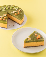 Vegan sea buckthorn and kiwi raw cake on paper yellow background. Minimalist food photography.