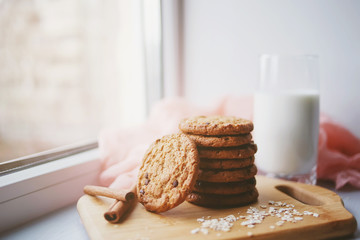 Oatmeal chocolate chip cookies with cinnamon and a glass of milk. Cookies on a wooden cutting board.