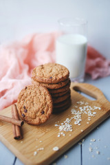 Oatmeal chocolate chip cookies with cinnamon and a glass of milk. Cookies on a wooden cutting board.