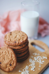 Oatmeal chocolate chip cookies with cinnamon and a glass of milk. Cookies on a wooden cutting board.