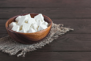 feta cheese, diced, in a wooden bowl on a burlap close-up. background with feta cheese in a wooden bowl.