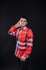 young guy in a plaid shirt posing on a black background photo studio