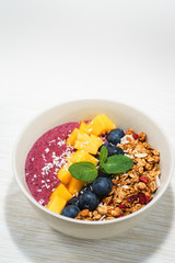 Handmade Bowl healthy tasty breakfast of yogurt, smoothie with granola, nuts, mango and berries.