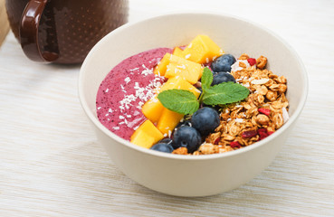 Handmade Bowl healthy tasty breakfast of yogurt, smoothie with granola, nuts, mango and berries.