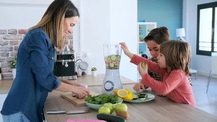 Video of two boys helping his mother to prepare a detox juice with blender in the kitchen at home. - Powered by Adobe