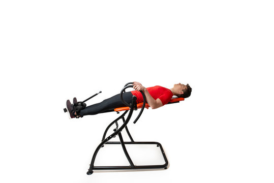 Man doing exercise on inversion table for his back pain, isolated on white
