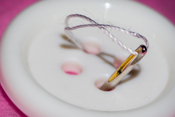 Fotografia macro de una aguja cosiendo un boton