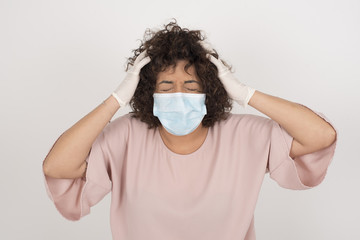 Shocked panic Caucasian girl wearing medical mask holding hands on head and screaming in despair and frustration while being late for plane, her eyes full of terror, mouth dropped open