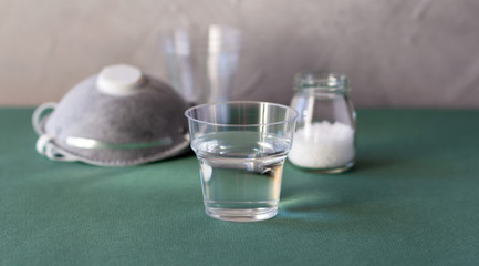 Plastic cup with salty water to rinse nose and throat as prevention and protection from viruses. Copy space