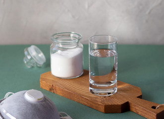 Glass with salty water to rinse nose and throat as prevention and protection from viruses. Jar with salt and medical mask. Covid-19 concept