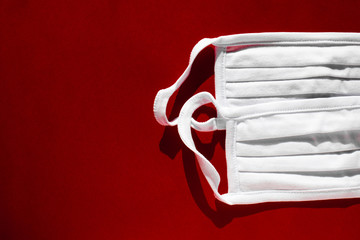 Covid protection. Breathing medical respiratory mask on red background. 
