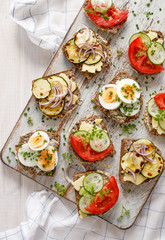 Vegetarian breakfast,  sandwiches made from homemade buckwheat bread with various toppings on a wooden rustic board, top view