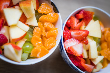 Fruit bowl: Strawberries, apple chunks, grapes and tangerines in a bowl