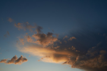 Fototapeta premium Beautiful evening blue sky at sunset with flaming bright light clouds. A warm summer evening.
