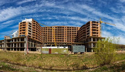 Work in progress on a new apartment block. Tall building under construction with cranes. Construction Site of New Building.