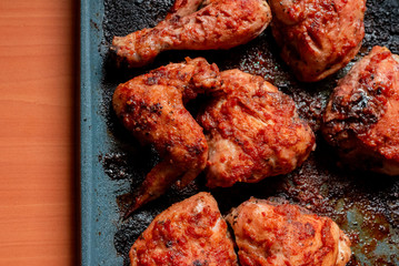Roasted chicken in barbecue sauce in a baking tray on a wooden table. Top view.