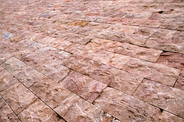 Empty surface covered with marble tiles, shown in angled diagonal perspective.