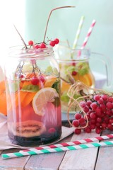 Fototapeta na wymiar Refreshing cocktail, detox water from organic fruits and berries, mint leaves in glass jugs on a wooden table, healthy nutrition