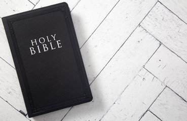 A Black Holy BIble on a White Wooden Table