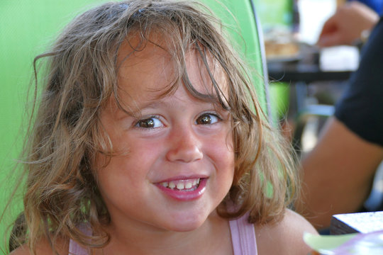 A 4 year old girl smils in a Toroni bar in Greece