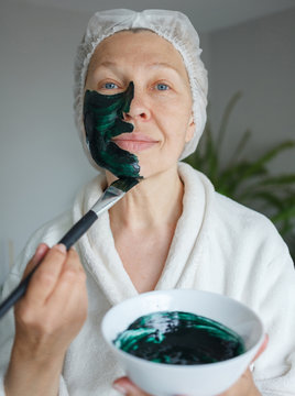 A woman makes herself a mask on her face from spirulina.