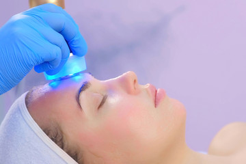 Cosmetologist doctor making phonophoresis procedure on woman face with hyaluronic acid gel, side...