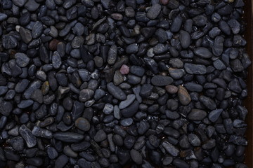 Fototapeta na wymiar Black Dark Pebbles For Background or Texture Moody Wet Stone surface gloomy abstract muted colors