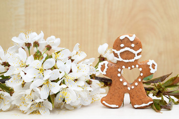 Gingerbread man with protective face mask surrounded by spring blooming twig - concept in coronavirus (COVID-19) time 