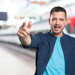Young man wearing a blue outfit. Pointing to the cam.