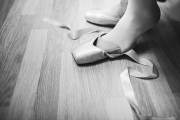 Lacing ballet slippers. Ballerina laces the ribbons of the pointes. BW lifestile photo. close-up of legs © EkaterinaKiseleva