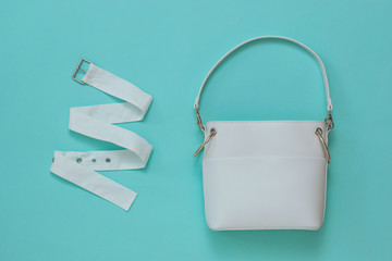 White women's bag and white fabric belt on a light background. Flat lay.