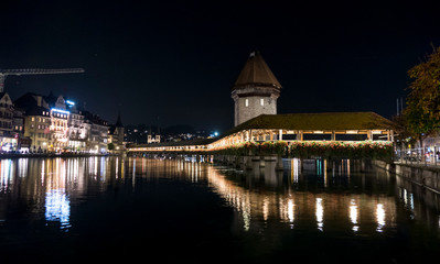 Fototapeta na wymiar Illuminated Lucerne and Chapel Bridge reflect on the river
