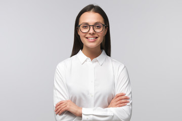 Young business lady, wearing eyeglasses and white collar shirt, looking at camera with positive...