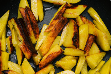 Fried potatoes closeup. Sliced potatoes are cooked in a pan. Fast food for lunch or dinner. Cooking at home.