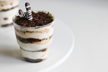 Classic tiramisu dessert in a glass and cup of coffee on light background. dessert with copy space closeup
